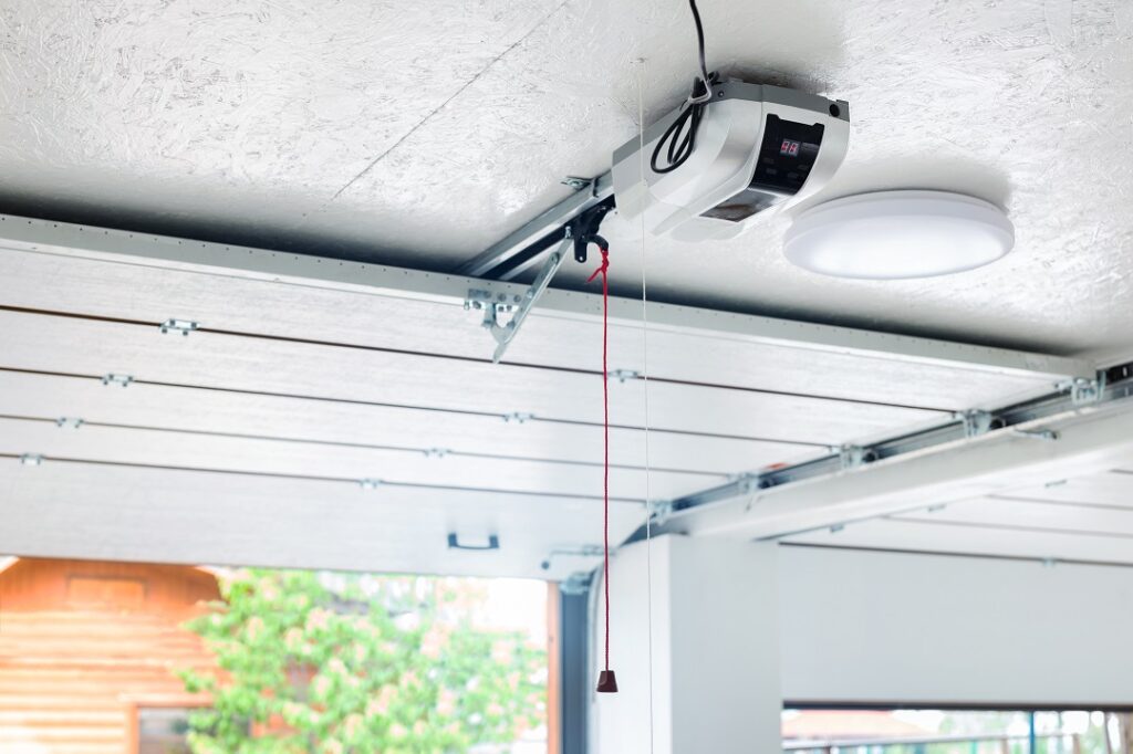 Öppningsdörr och automatisk garageportöppnare elektrisk motorväxel monterad i tak med nödsladd. Dubbelplats tomt garageinteriör med rullande entréport.