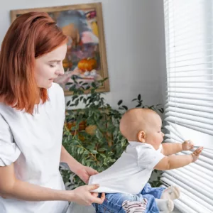 Barnsäkerhet mamma fixar tröjan på ett barn som håller i persinner